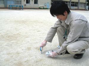 学校の校庭で放射線量を測定する市職員の写真